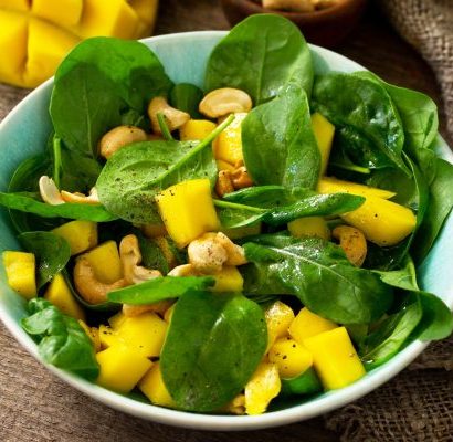 Healthy salad with spinach, mango, pecan and vinaigrette dressing