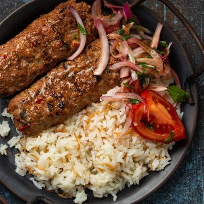 Traditional Turkish dish meat kebab with rice and vegetables in pan